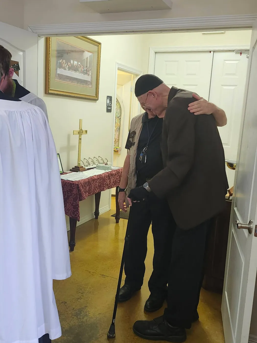 A parishioner embraced in welcome just inside the church door on a Sunday morning