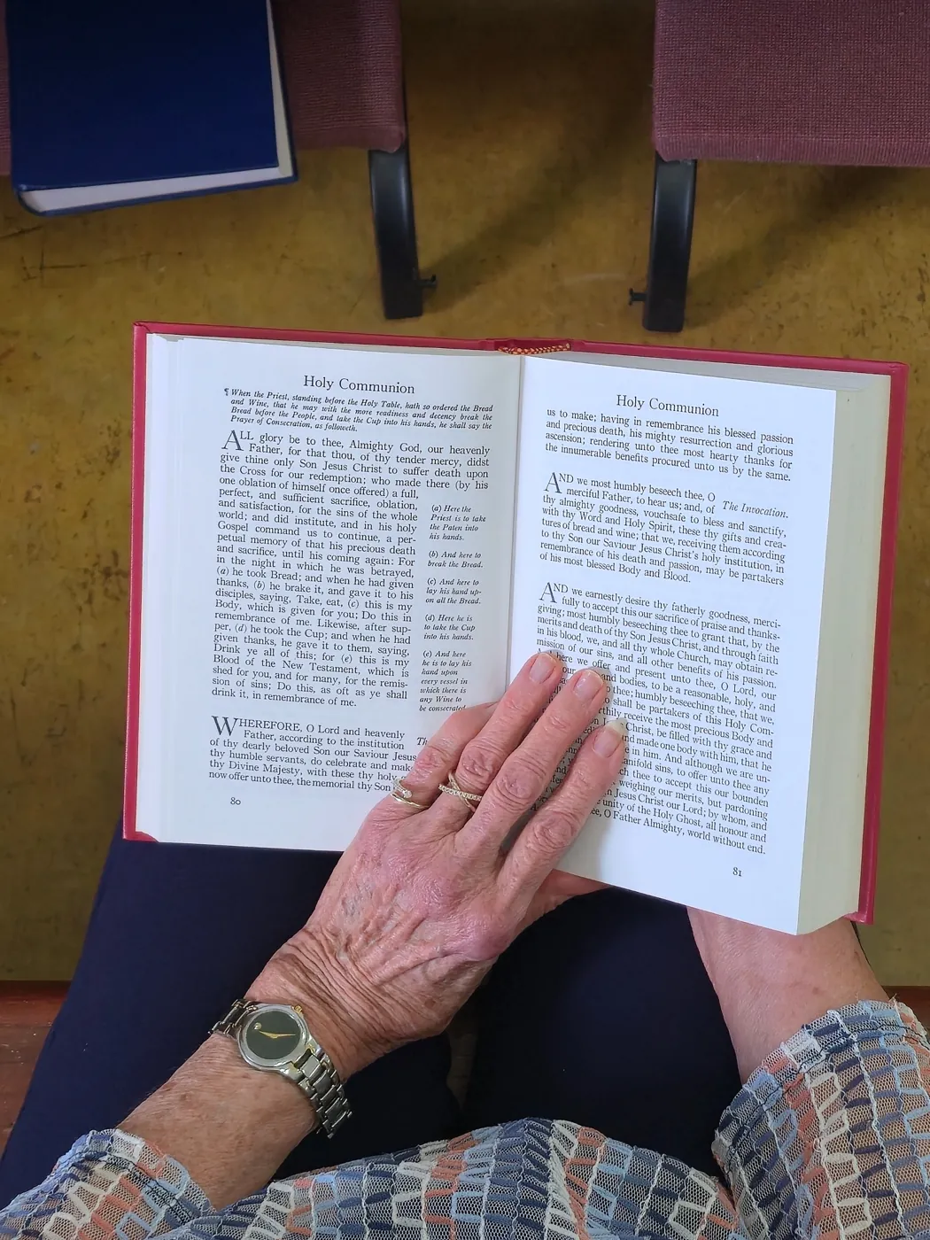 Hands holding the 1928 Book of Common Prayer open to the Prayer of Consecration